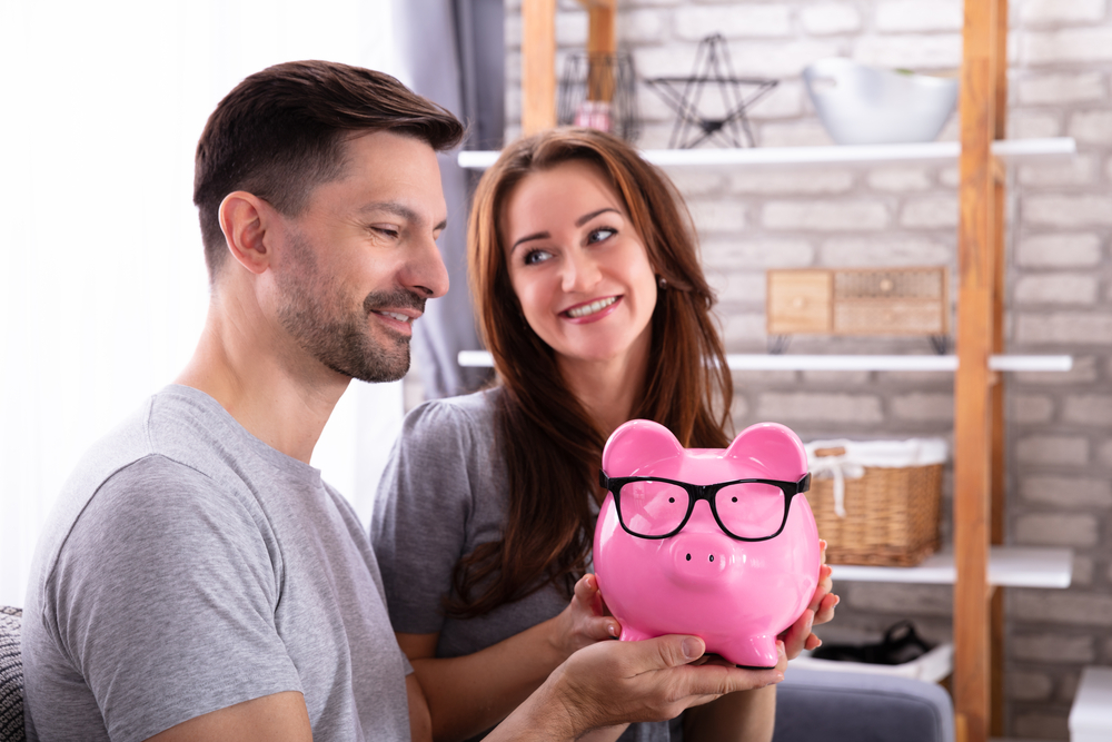 A couple holding a piggy bank with glasses