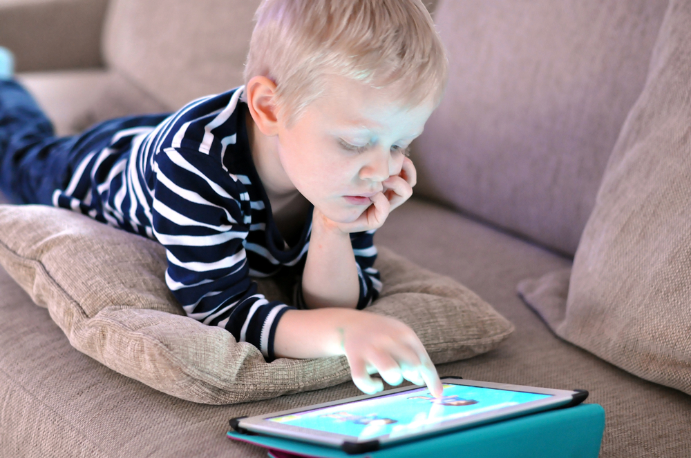 A child is playing a game on a tablet.