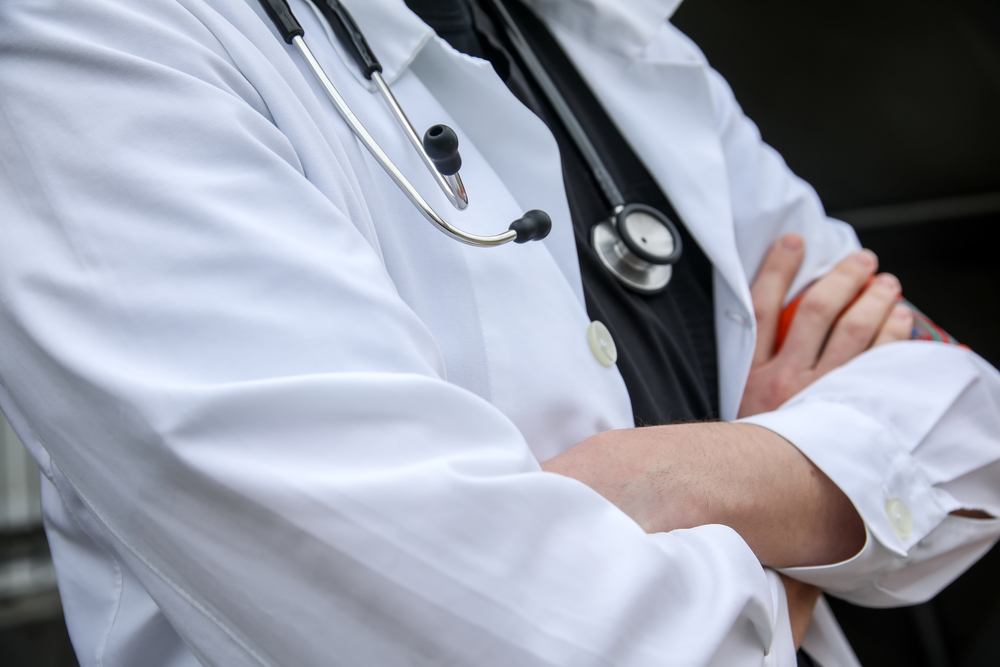 Physician in a lab coat with arms folded.