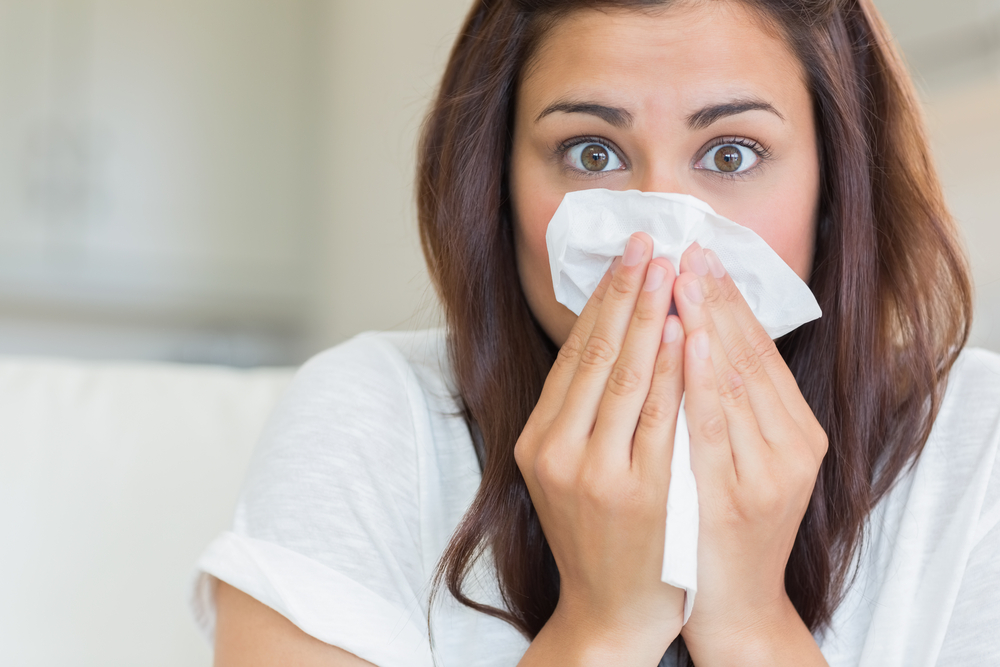 Woman sneezing into a tissue