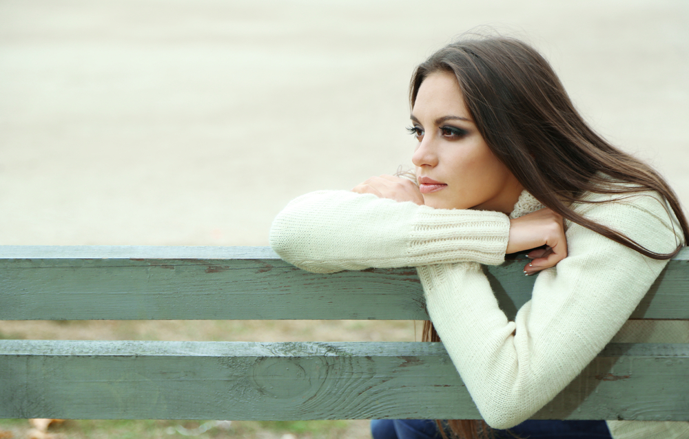 A woman is sitting alone on a bench.