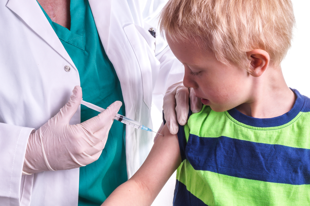 A nurse is giving a boy a flu shot.