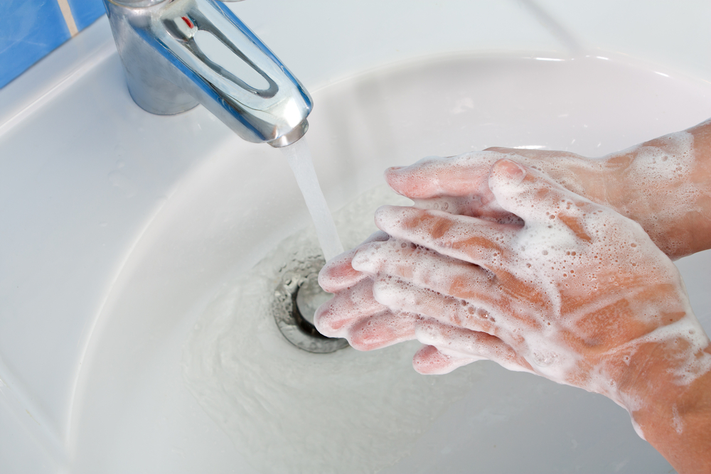 An individual washing his hands with soap and water at a sink.