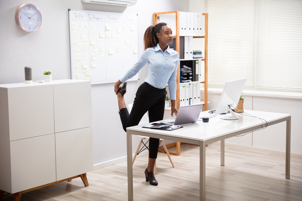 A woman stretching in her office on break.