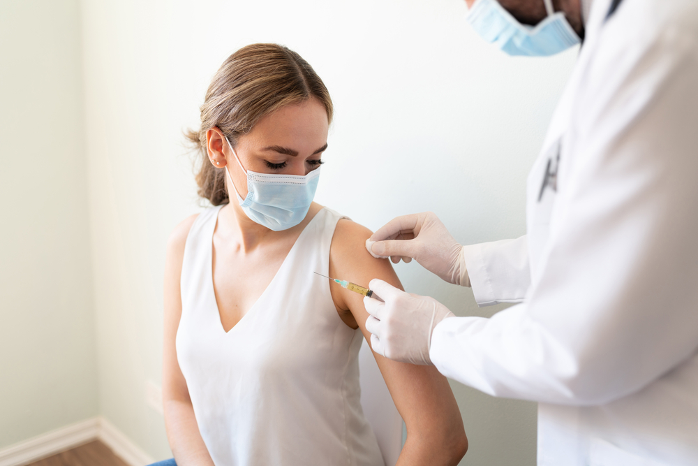 A doctor is about to give a female patient a COVID vaccine injection.