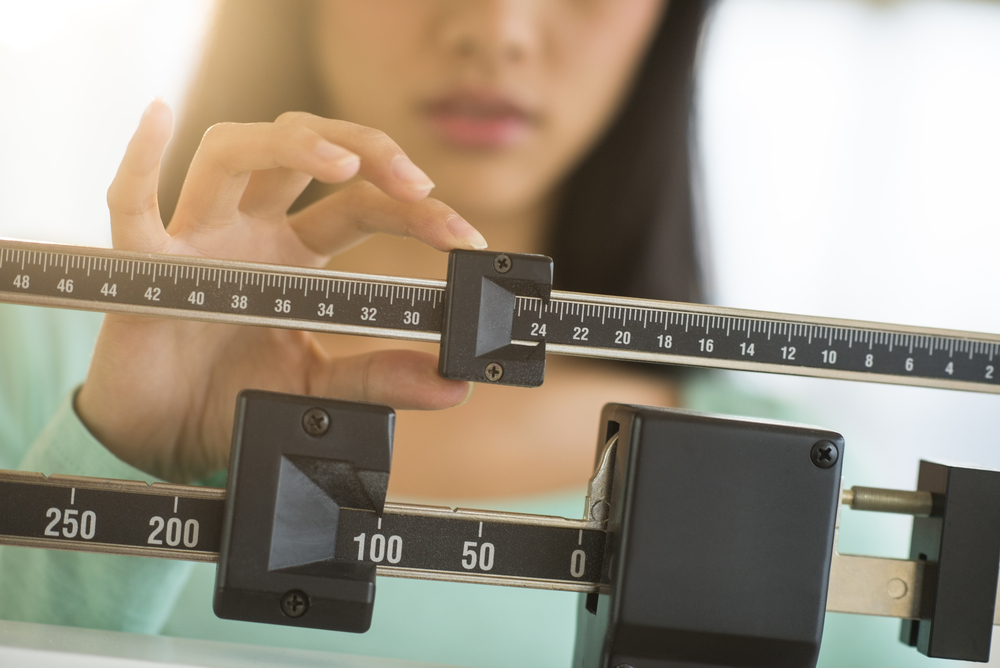 A woman measuring her weight on a physician scale